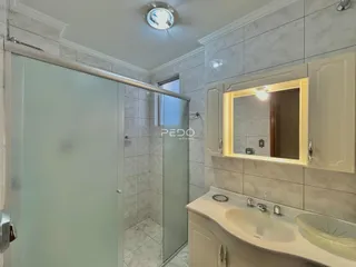 Banheiro com revestimento de azulejo claro e bancada branca.