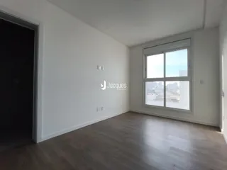 Ambiente interno com piso de madeira e grande janela de vista para a cidade.
