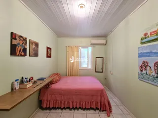 Quarto com cama e janela em ambiente claro.