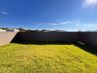 Vista de um gramado verde extenso sob um céu azul claro.