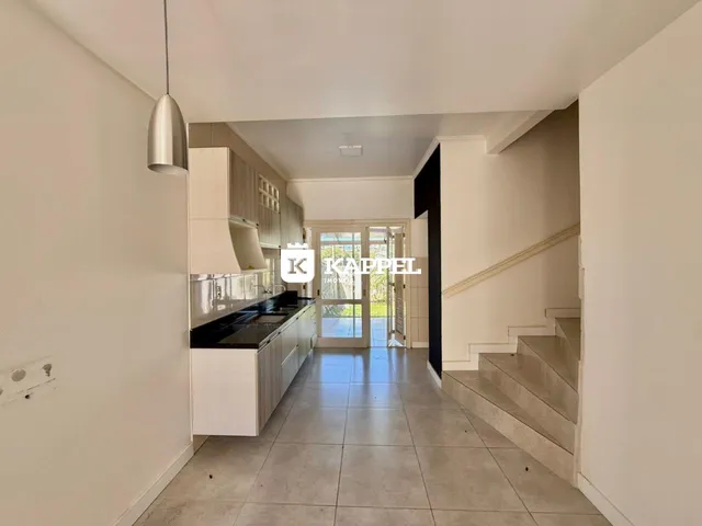 A foto mostra uma cozinha com armários brancos e piso de cerâmica.