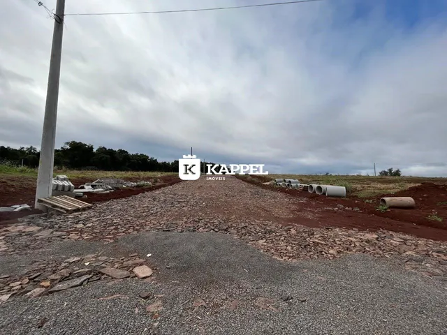 Foto externa de um terreno com terra e tubulações em uma área rural.