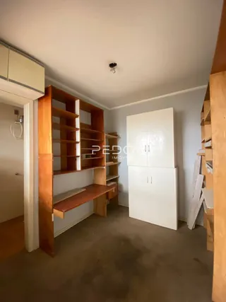 Interior de um ambiente com estantes de madeira e armários brancos.