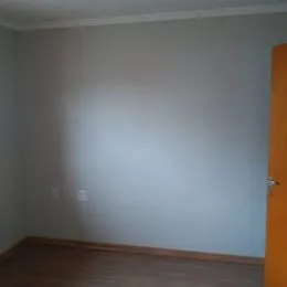 Foto interna de um cômodo com piso de madeira.