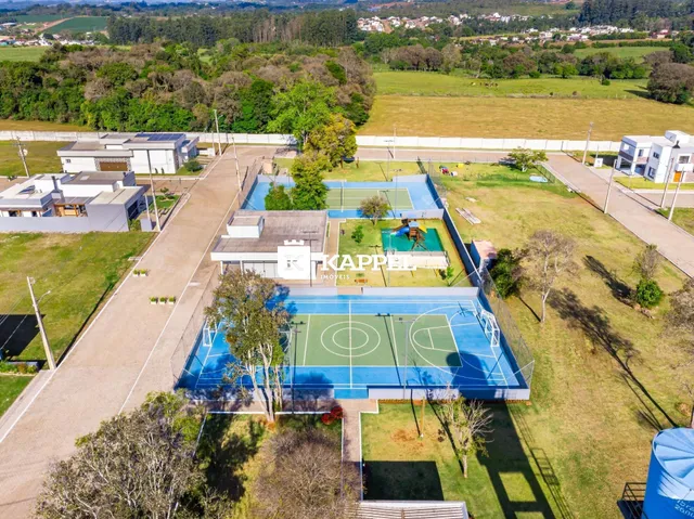Vista aérea de um complexo esportivo externo com quadras de basquete e futebol em uma propriedade.