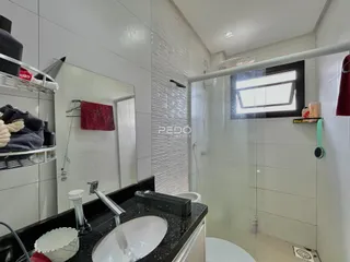 Foto de um banheiro com revestimento cerâmico e box de vidro.