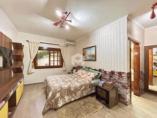 Quarto com cabeceira de tijolos aparentes e janela de madeira.