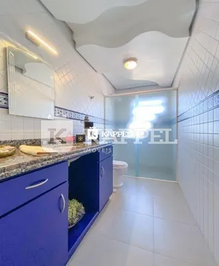Vista interna de uma cozinha com armários azuis e revestimento de azulejos brancos.