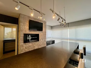 Ambiente de sala com parede de pedra e ilha de cozinha.
