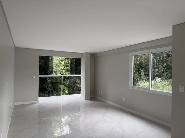 Sala ampla com grandes janelas que oferecem vista para a vegetação externa.