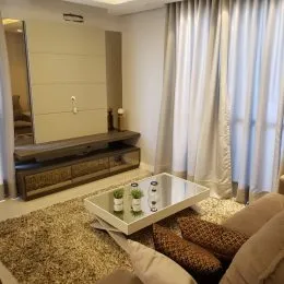 Sala de estar com cortinas brancas e piso de carpete.