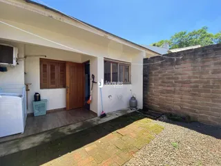 Fachada de uma residência com parede de tijolos aparentes e um pátio coberto.