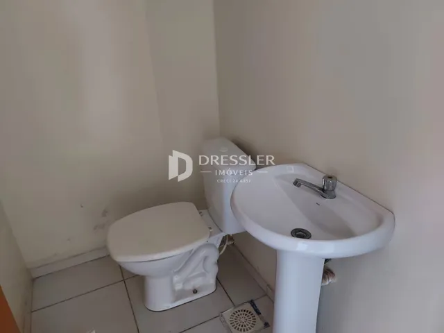 Foto de um banheiro com vaso sanitário e pia brancos.