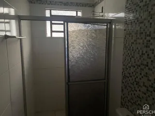 Foto de um banheiro com revestimento de azulejos brancos e box de vidro.