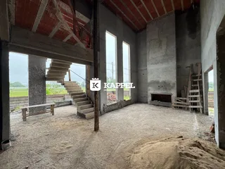 Interior de uma estrutura em construção com paredes de concreto aparente e escadas expostas.