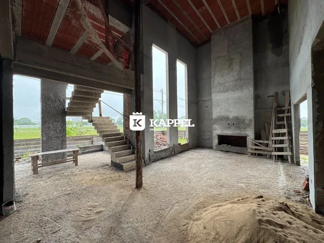 Interior de uma estrutura em construção com paredes de concreto aparente e escadas expostas.