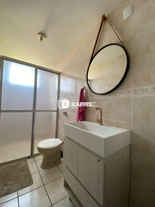 Banheiro com pia e revestimento de azulejos brancos.