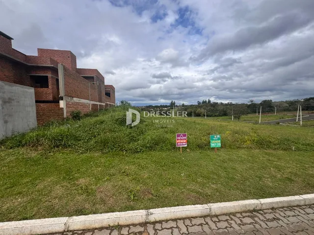 Vista externa de uma propriedade com gramado e construção de tijolos vermelhos.