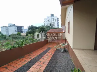Fachada de uma residência com calçada de tijolos e cascalho.