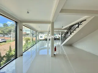 Vista interna de um hall amplo com piso claro e escadaria de ferro.