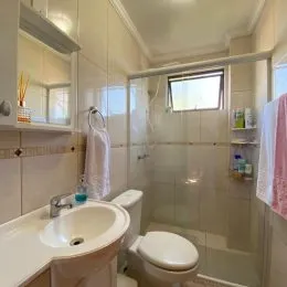 Foto de um banheiro com revestimento de azulejos brancos e vaso sanitário.