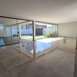 Ambiente interno com piso claro e grandes portas de vidro que dão acesso a uma área externa.