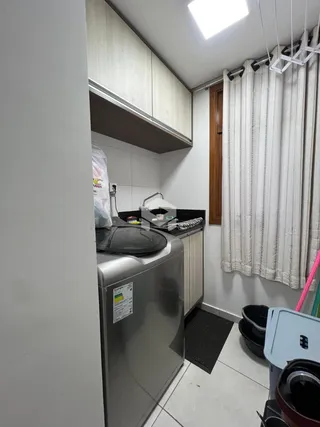 Vista interna de uma área de serviço com máquina de lavar roupa.