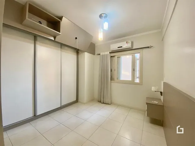 Foto de uma sala de estar clara com piso de cerâmica branca e armários embutidos.