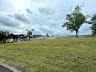 Vista de um terreno gramado com árvores ao fundo.