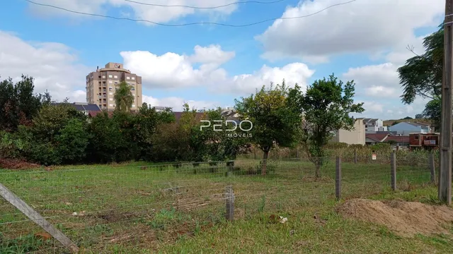 Campo gramado com cerca delimitando uma propriedade residencial.