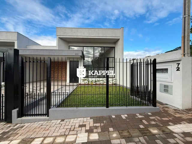 Fachada de uma residência moderna com cerca preta e jardim frontal.