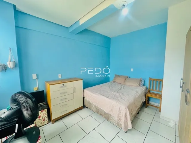 Quarto com cama e cômoda em ambiente de sala.
