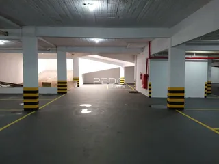 Área interna de um prédio com pilares e piso de concreto.