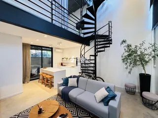 Interior de uma sala de estar moderna com escadaria e grandes janelas.
