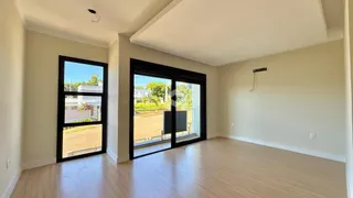 Sala de estar com piso de madeira e grandes janelas de vidro.