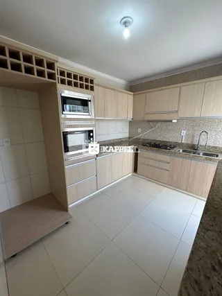 Cozinha com armários de madeira clara e piso de cerâmica.