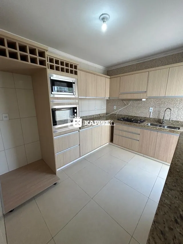 Cozinha com armários de madeira clara e piso de cerâmica.