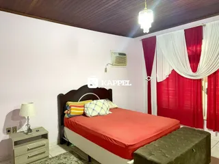 Quarto com cama de casal e cortinas vermelhas.