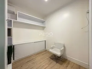 Ambiente interno com piso de madeira e estantes brancas.