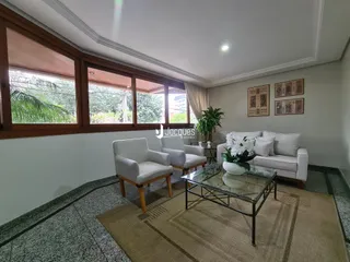Sala de estar com grandes janelas e vista para a vegetação externa.
