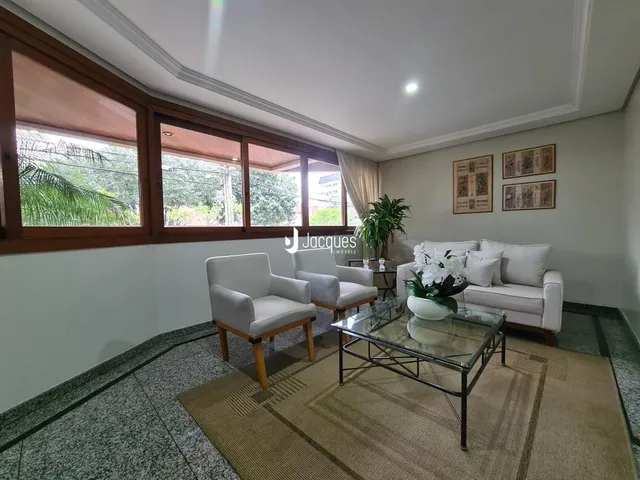 Sala de estar com grandes janelas e vista para a vegetação externa.