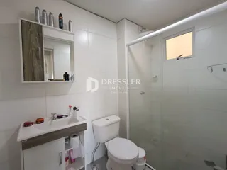 Banheiro com box de vidro e revestimento branco.