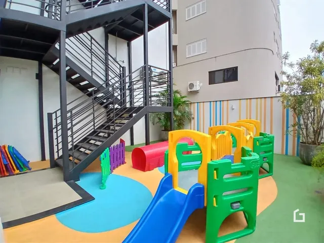 Área externa com playground e fachada de um prédio em Lajeado.