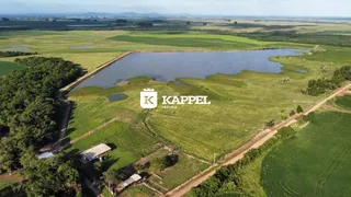 Vista aérea de uma propriedade rural com campos verdes e um corpo d'água.
