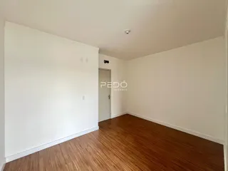 Sala de estar com piso de madeira e paredes brancas.