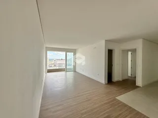 Interior de um ambiente com piso de madeira e grande janela.