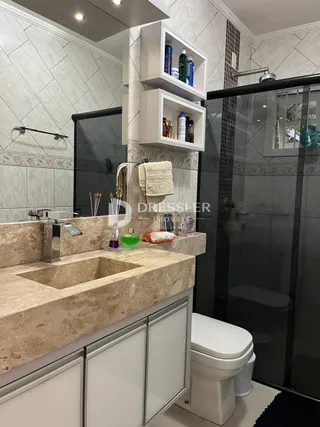 Banheiro com bancada de pedra e box de vidro.