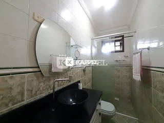 Banheiro com revestimento de azulejos brancos e bancada escura.