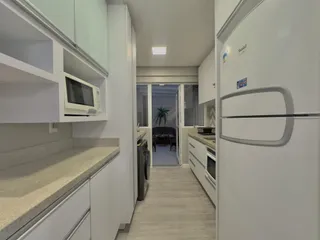 Vista de uma cozinha com armários brancos e piso claro.