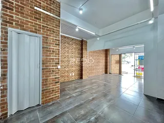 Interior de um espaço amplo com paredes de tijolo aparente e piso de concreto.